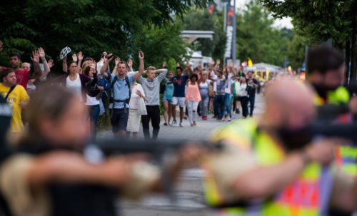 Police escorts evacuated people from the shopping mall (the Olympia Einkaufzentrum (OEZ) in Munich on July 22, 2016 following a shootings earlier. At least one person has been killed and 10 wounded in a shooting at a shopping centre in Munich on Friday, German police said. / AFP PHOTO / STR