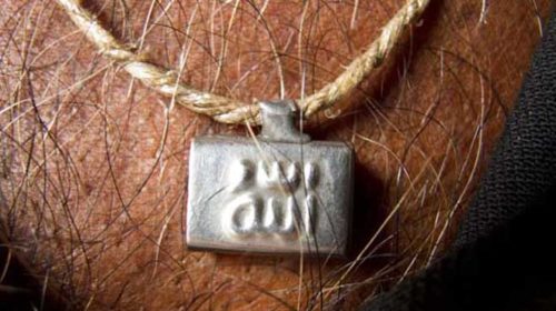 Most people have a 'tabiz'. They are usually small pieces of paper with writings from the Quran, packed in little tubes or small caskets. They are often tied around hte waist or the arm, or as in this case worn as a pendant.