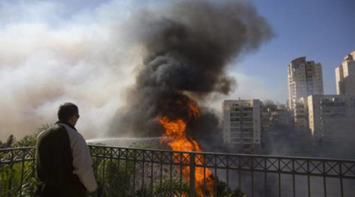 A man watches wildfires in Haifa, Israel, Thursday, Nov. 24, 2016. Israeli police have arrested four Palestinians in connection with one of several large fires that damaged homes and prompted the evacuation of thousands of people in the past few days. Police are investigating the causes, including possible arson. Windy and hot weather have helped fan the flames. The blazes started three days ago near Jerusalem and in the north. Hundreds of homes were damaged. Russia, Italy and other countries are assisting the Israeli firefighters.(AP Photo/Ariel Schalit)